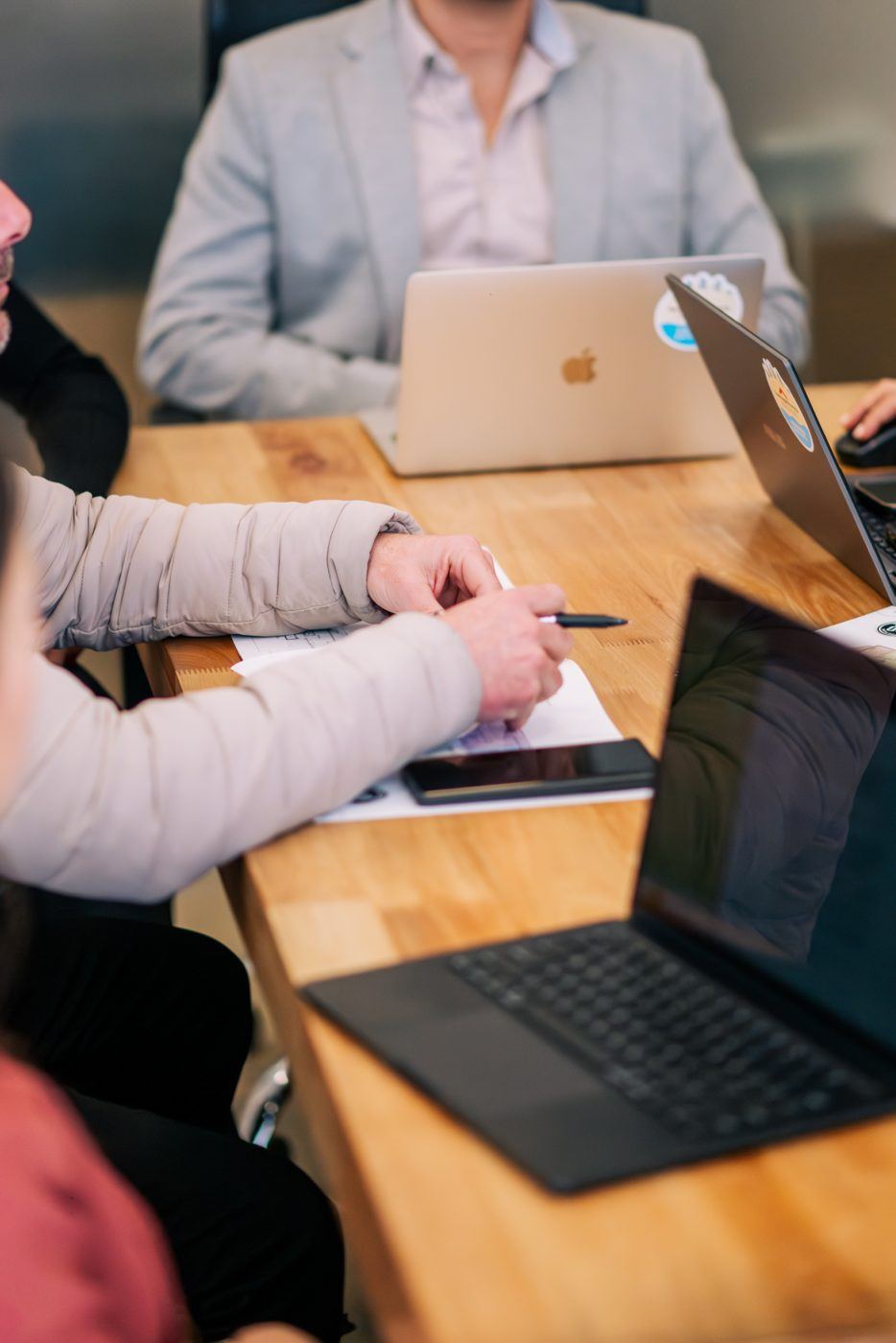 Comprador y asesor repasando los números de una compra sobre la mesa, con planilla y notebook