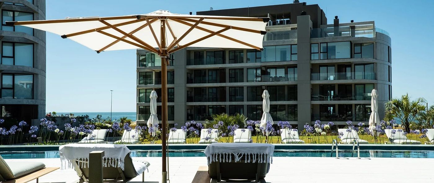 Piscina exterior con sombrilla y agapantos, con el bloque ya entregado detrás