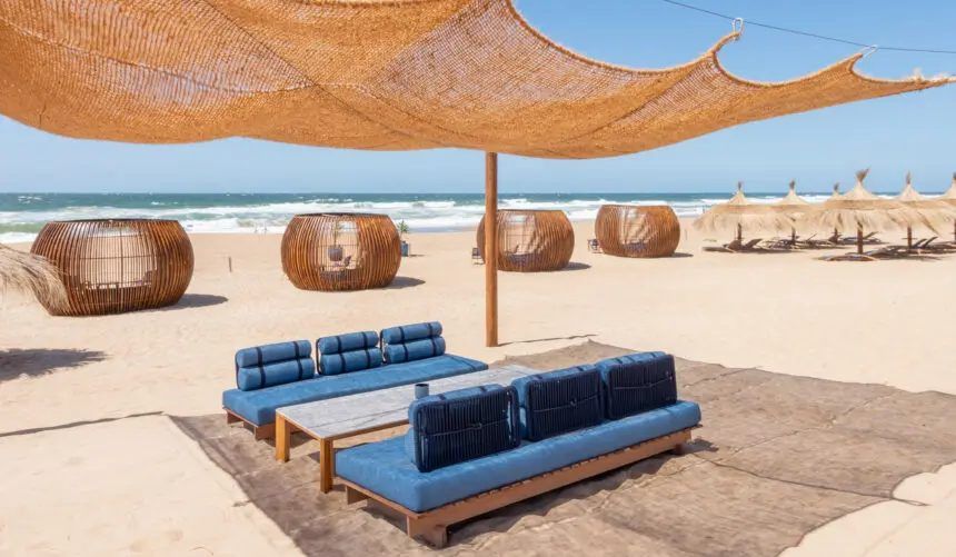 Livings del beach club bajo la media sombra, con el mar detrás