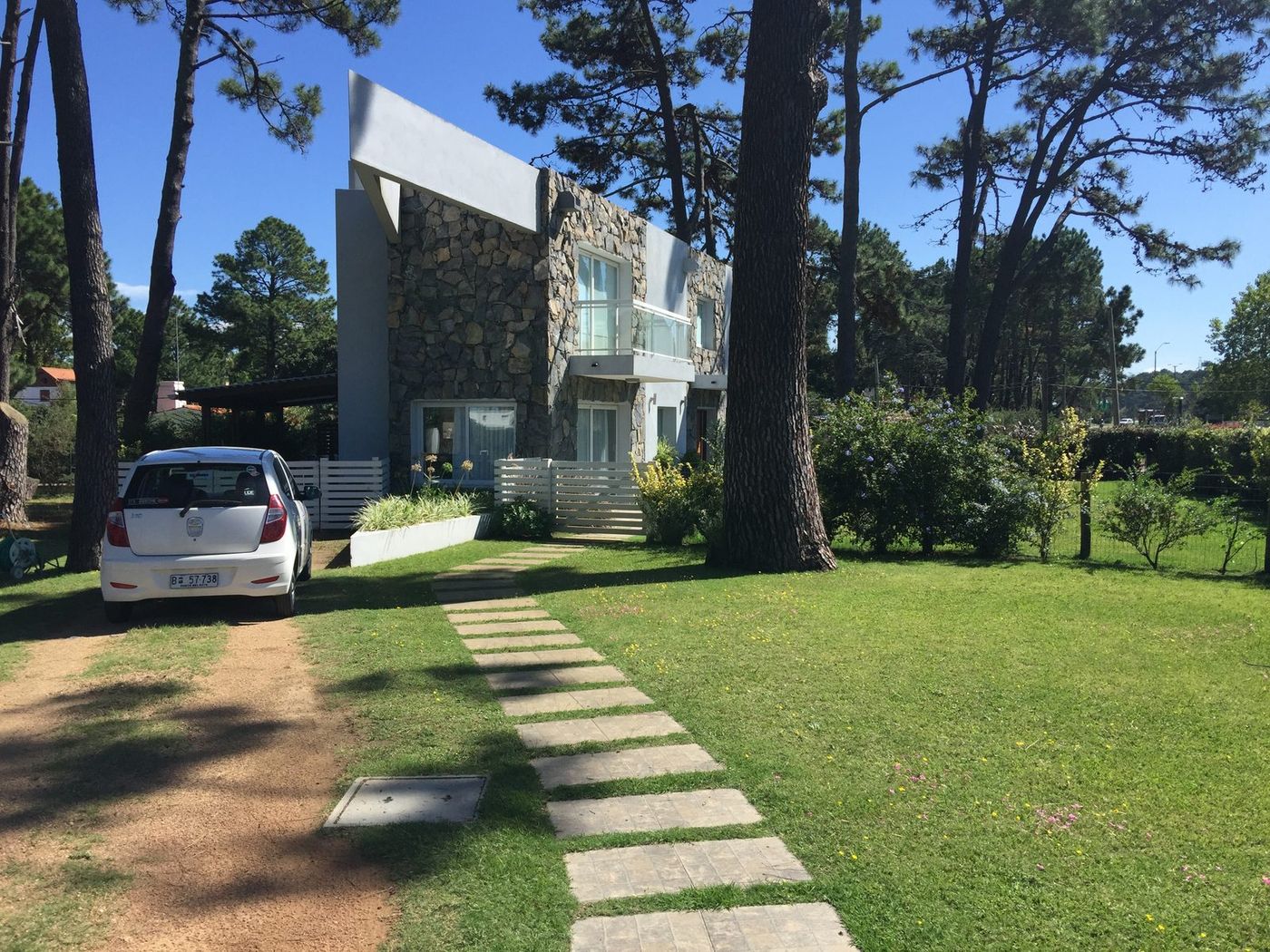 Frente de la casa de piedra, con un auto estacionado adelante