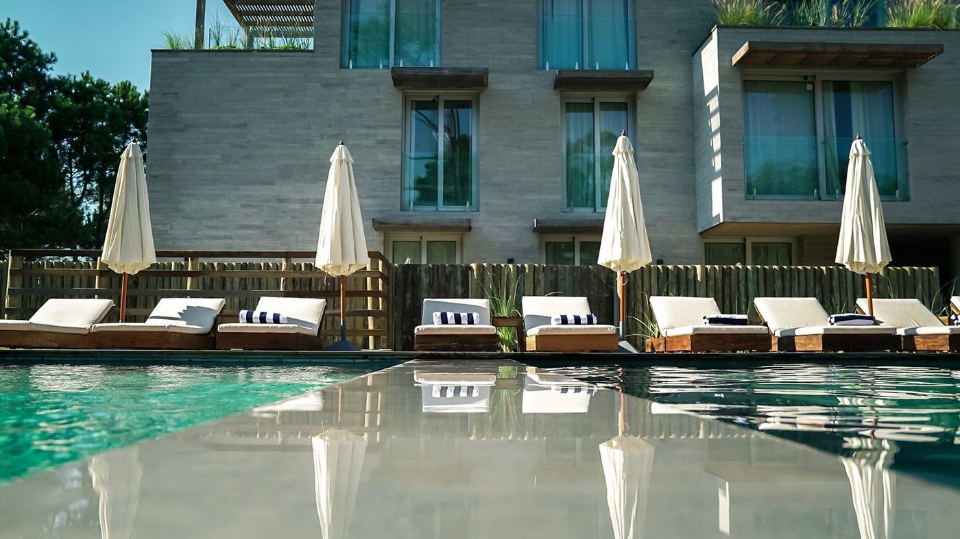 Piscina con reposeras, sombrillas y toallas de rayas al pie del edificio