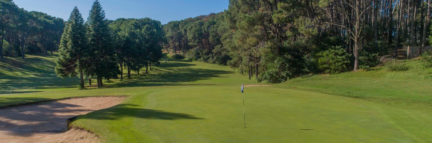Green de golf de Club del Lago con la bandera, los bunkers y el bosque