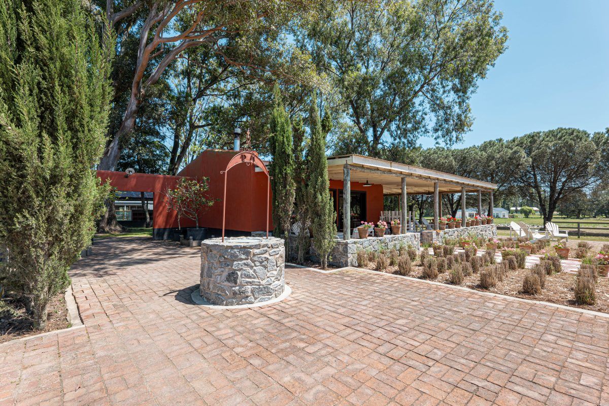 Patio de adoquines con el aljibe de piedra y la galería del club house