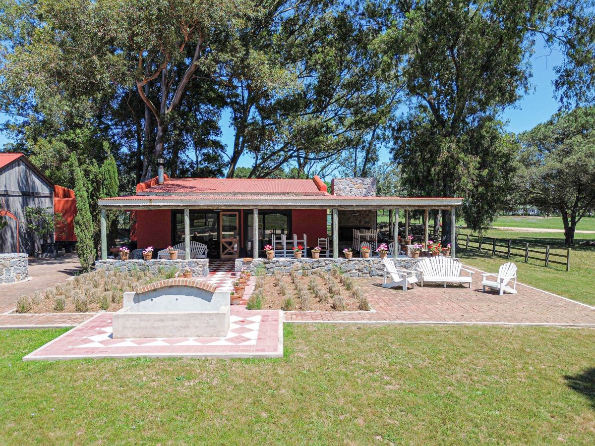Club house de Don Miguel con techo rojo, jardines de lavanda y sillones blancos