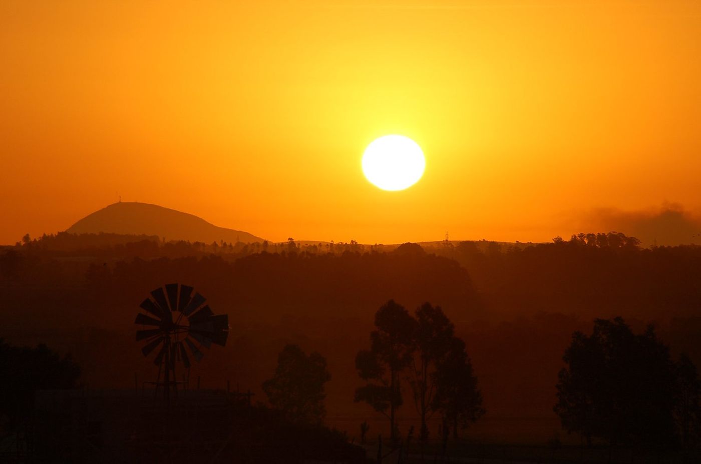 Atardecer naranja con un molino y el Cerro Eguzquiza en silueta