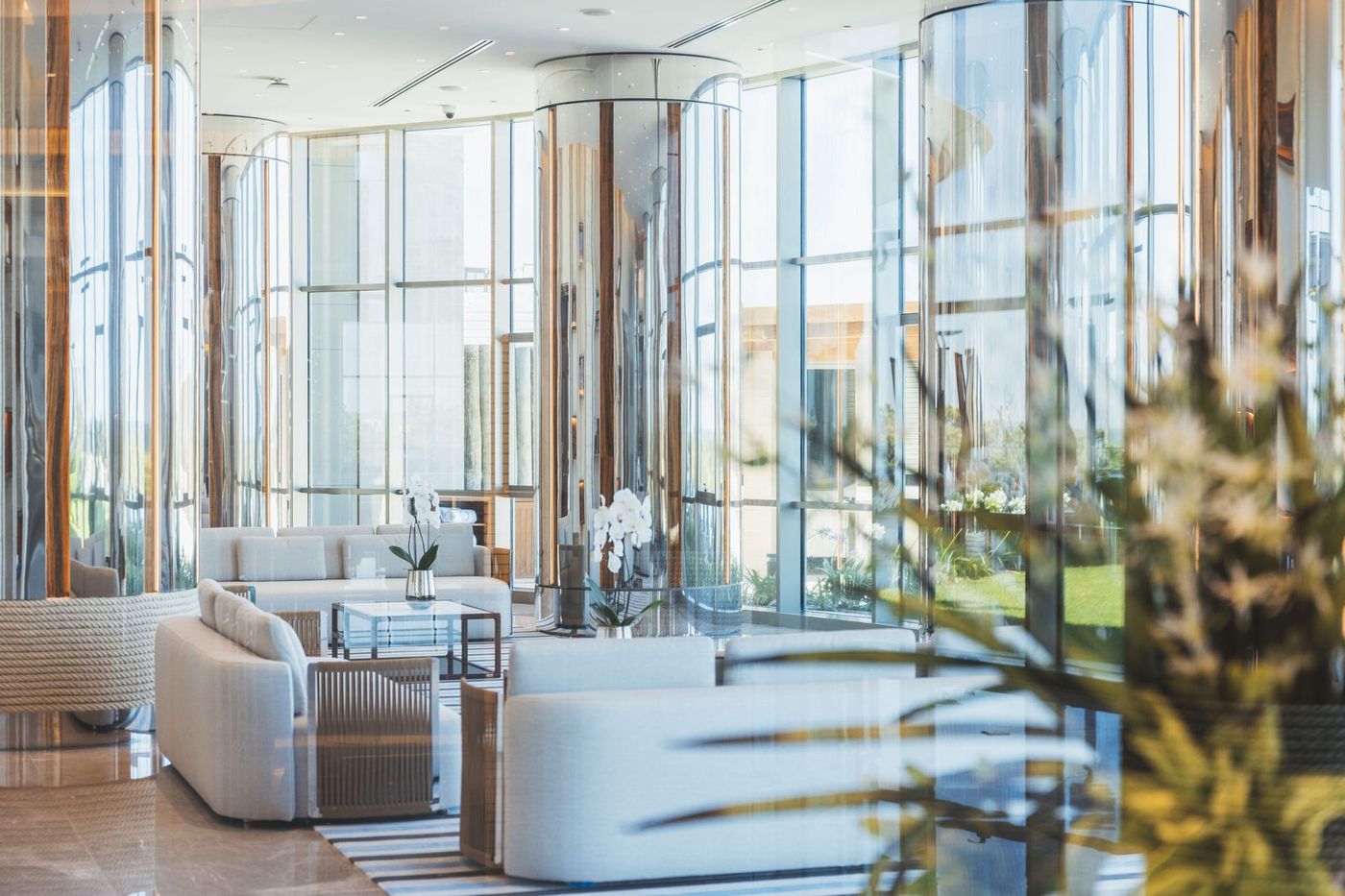 Lobby de Fendi Château con columnas espejadas, orquídeas y vista al jardín