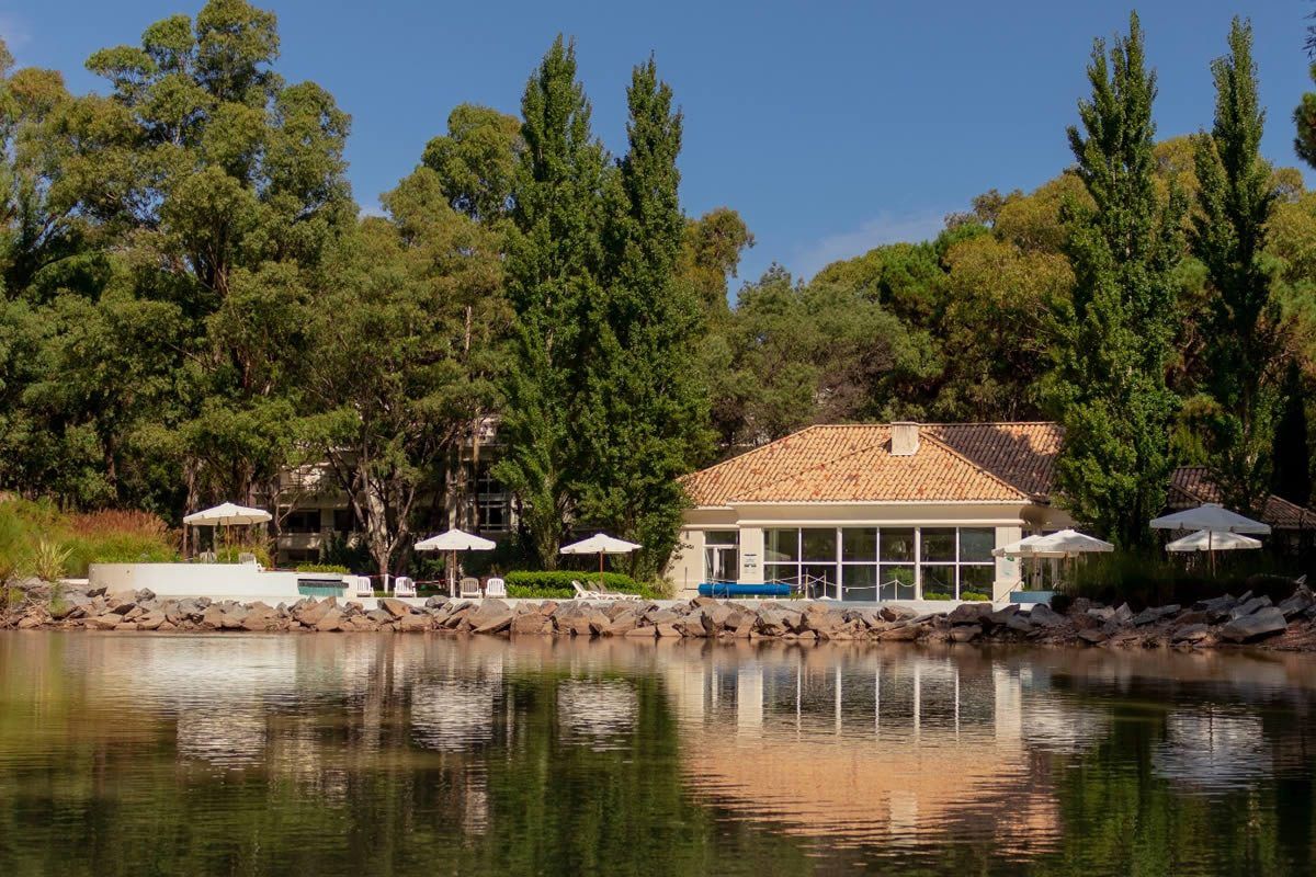 Clubhouse de tejas con sombrillas y piscina, visto desde el lago