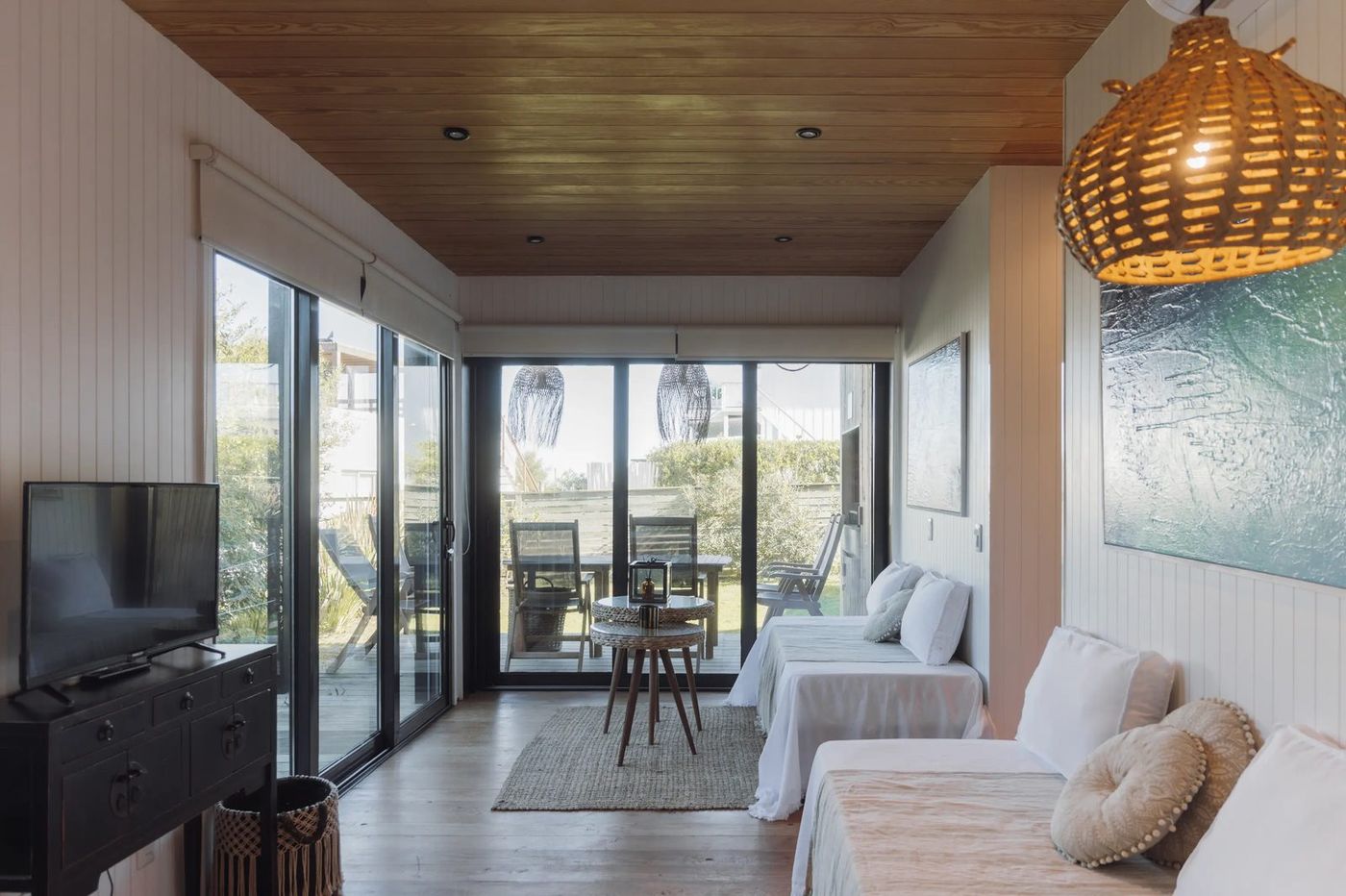 Living con techo de madera, ventanales y salida al deck