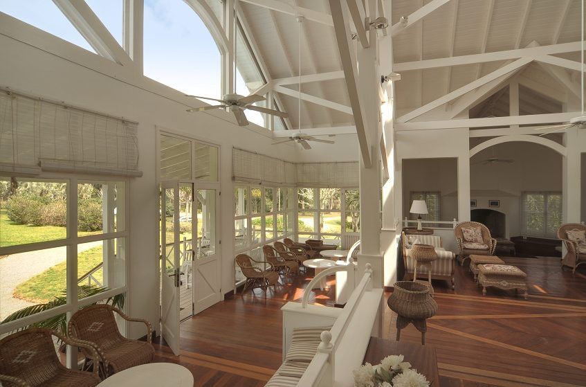 Interior del club house con techos altos y muebles de mimbre