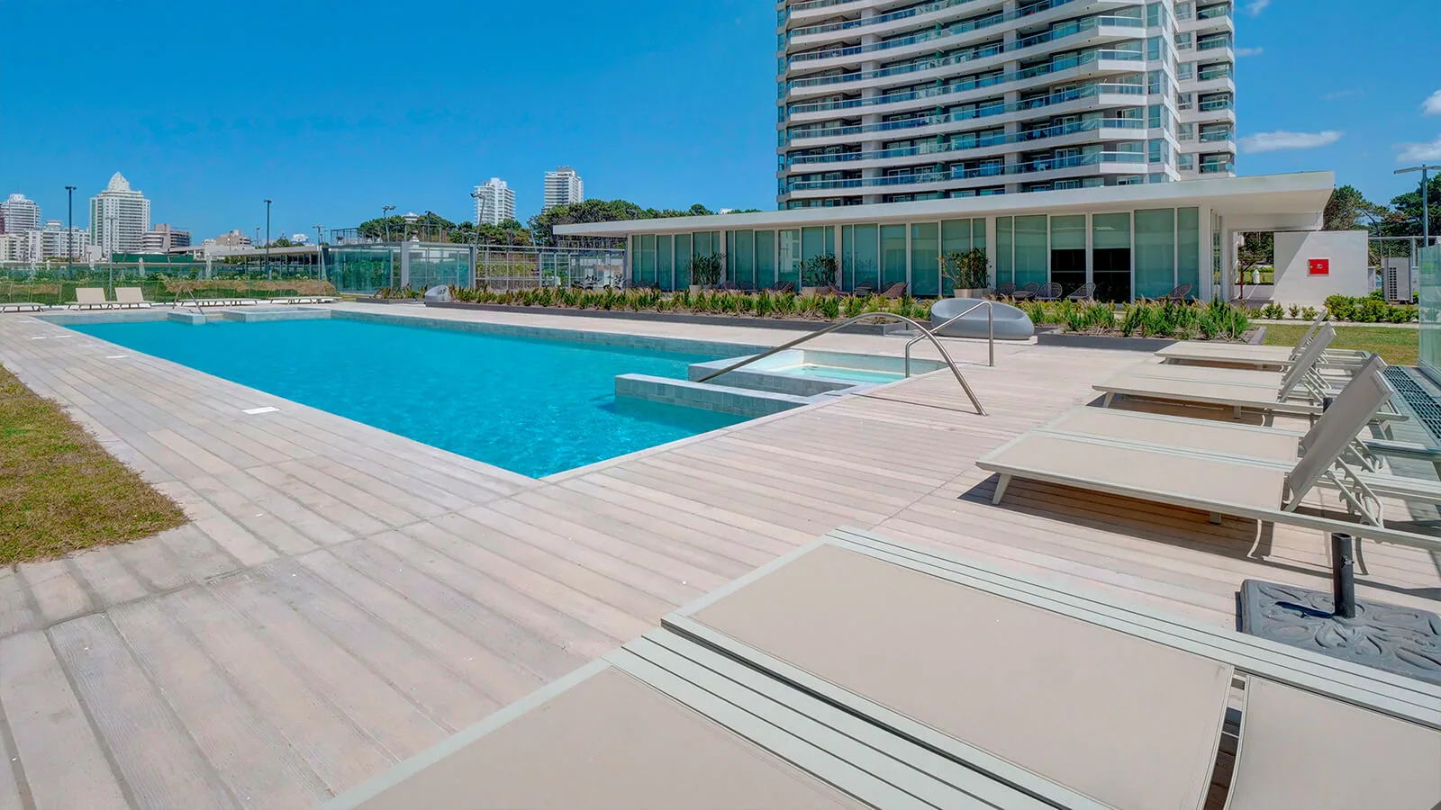 Piscina exterior con el clubhouse vidriado y la torre detrás