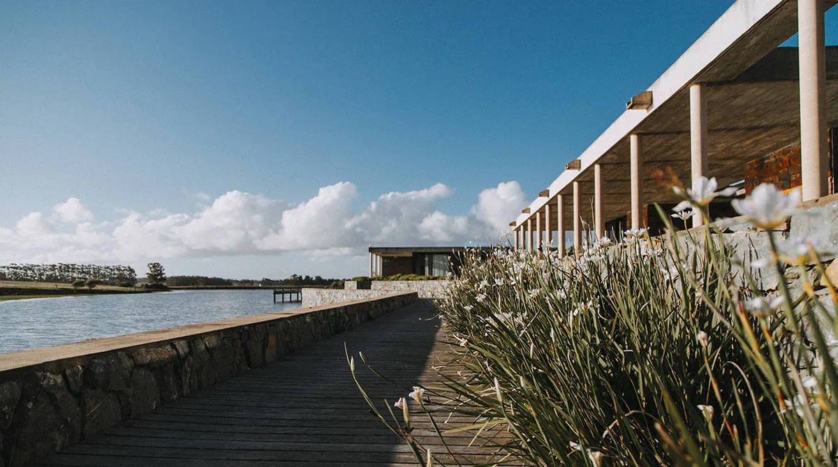 Pasarela de madera junto al lago de Lomas de San Vicente, con la pérgola de La Masía