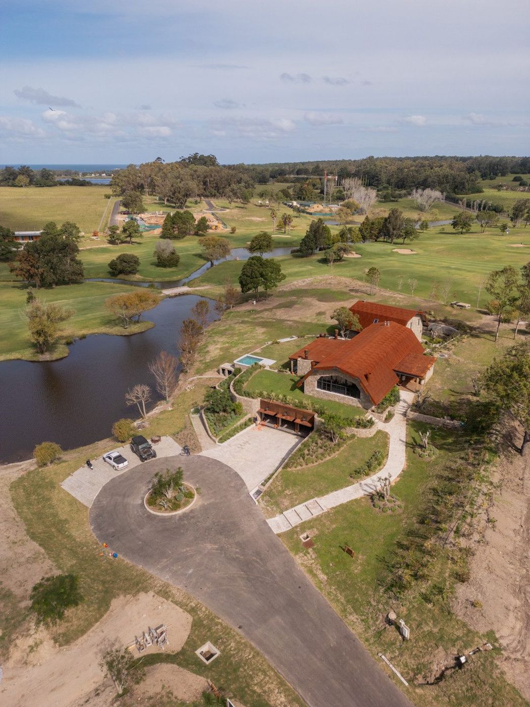Aérea de una casa de techo corten junto a los fairways de un campo de golf