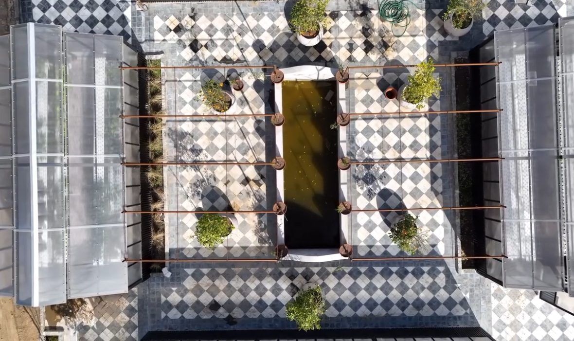 Cenital del patio de damero con el estanque, la pérgola y los invernaderos