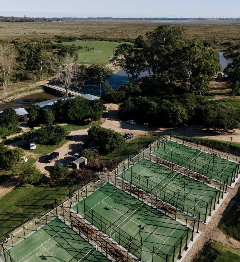 Aérea de las canchas de tenis y pádel, con el arroyo y el campo detrás
