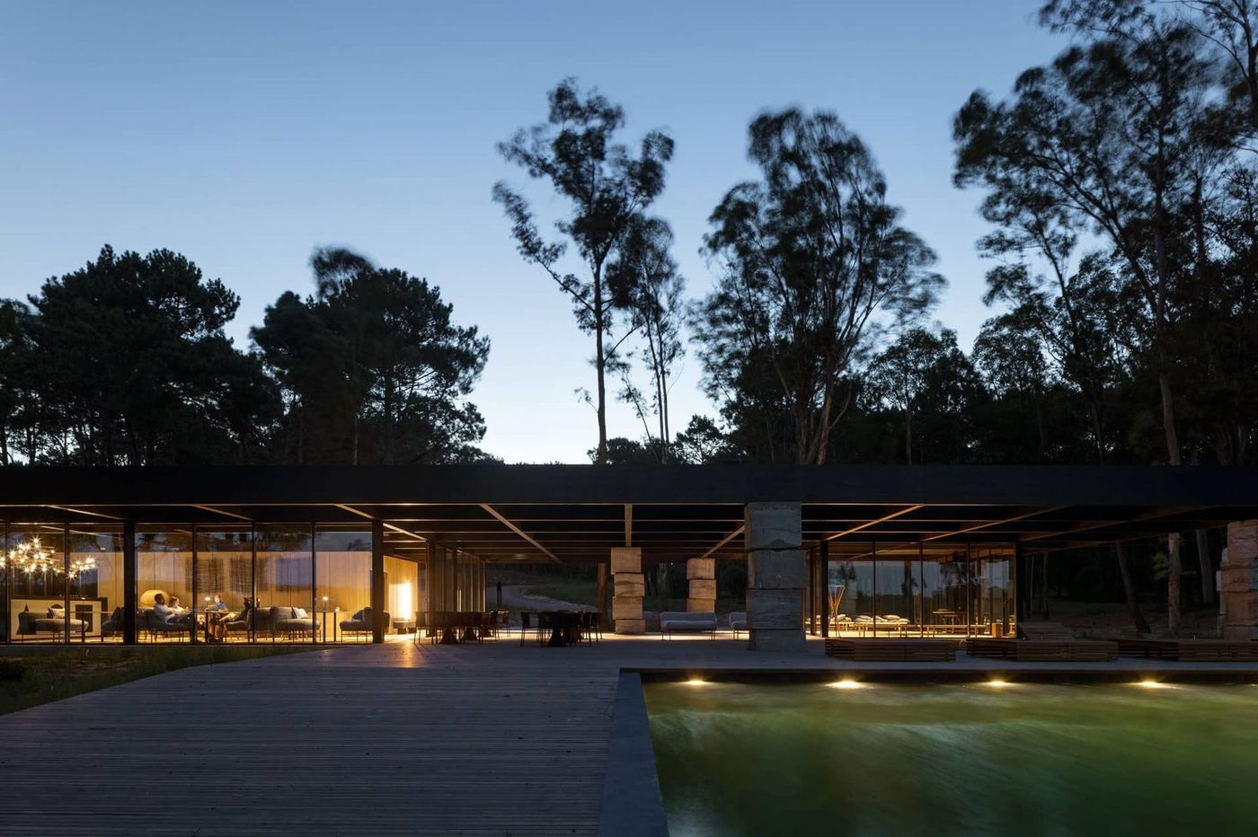 El club house completo con la piscina iluminada, al anochecer