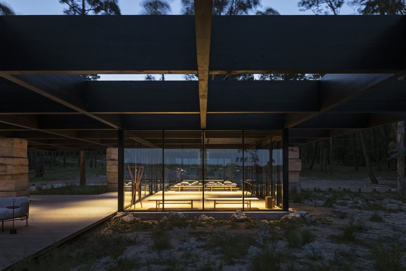 El pabellón de vidrio de la sala de yoga, iluminado de noche entre el bosque