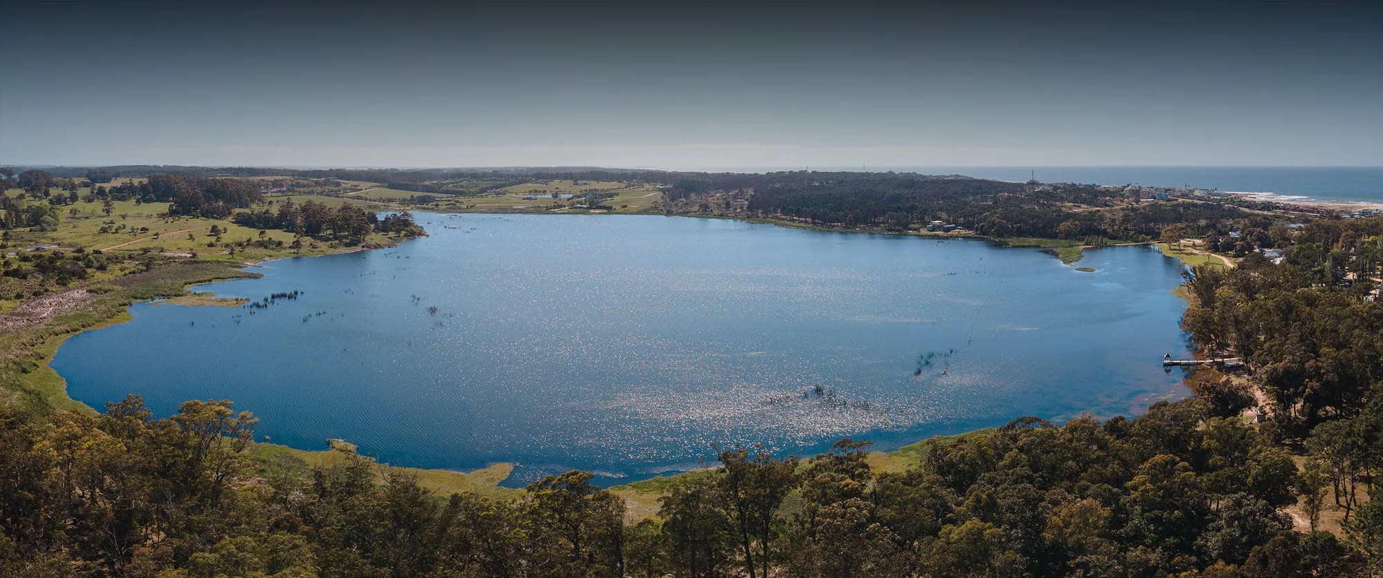 Aérea de la Laguna Blanca en Reserva Montoya, con el bosque, La Barra y el mar al fondo