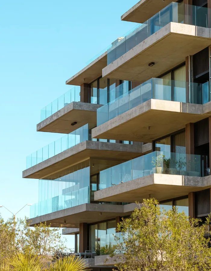 Primer plano de los balcones escalonados de hormigón y vidrio, con vegetación
