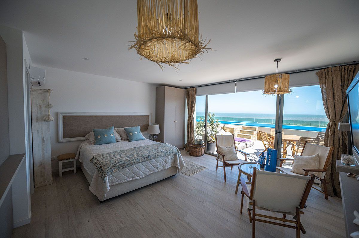 Dormitorio con la cama frente al deck, la piscina y el mar