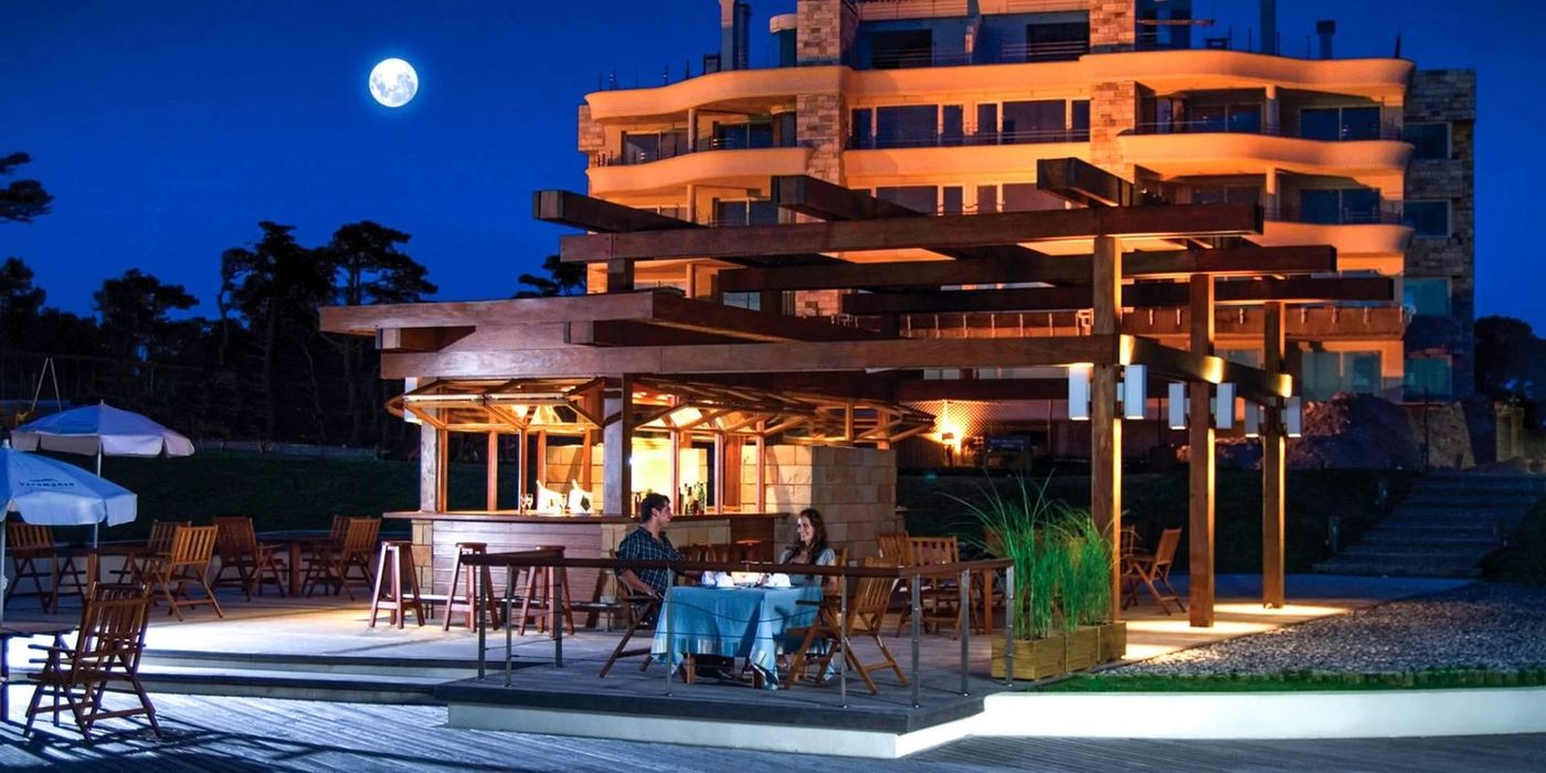 Nocturna del bar parrillero iluminado, con el edificio detrás y luna llena