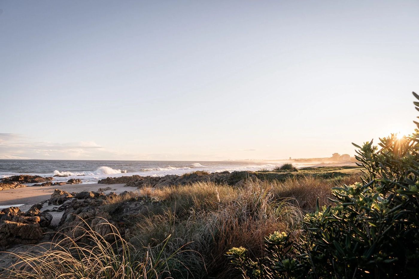 Costa rocosa con la rompiente y la silueta de Punta del Este a contraluz