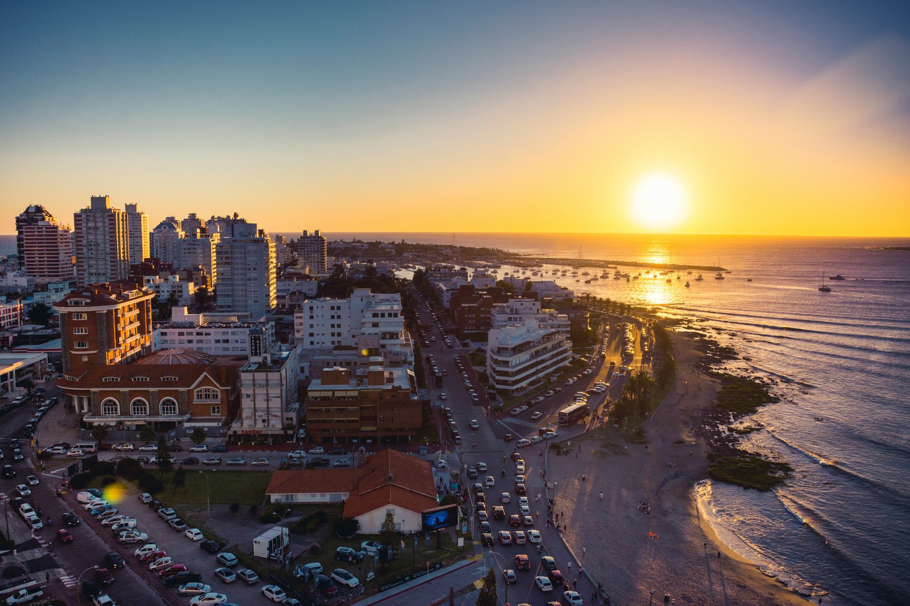 Vista aérea de la península de Punta del Este al atardecer, con el puerto y los veleros