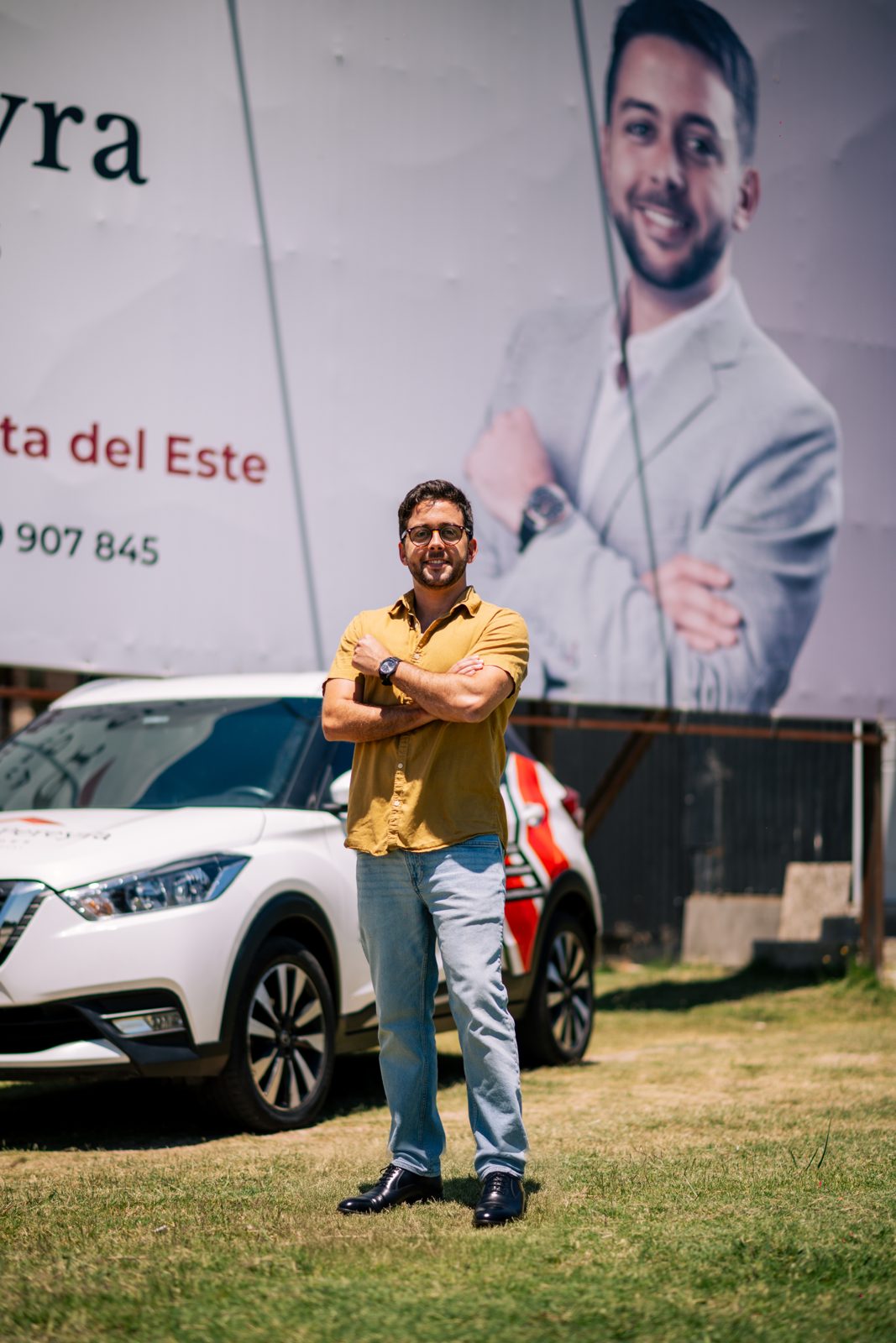 Santiago Pereyra junto a la camioneta de Santiago Pereyra Propiedades, frente al cartel de la firma en Punta del Este